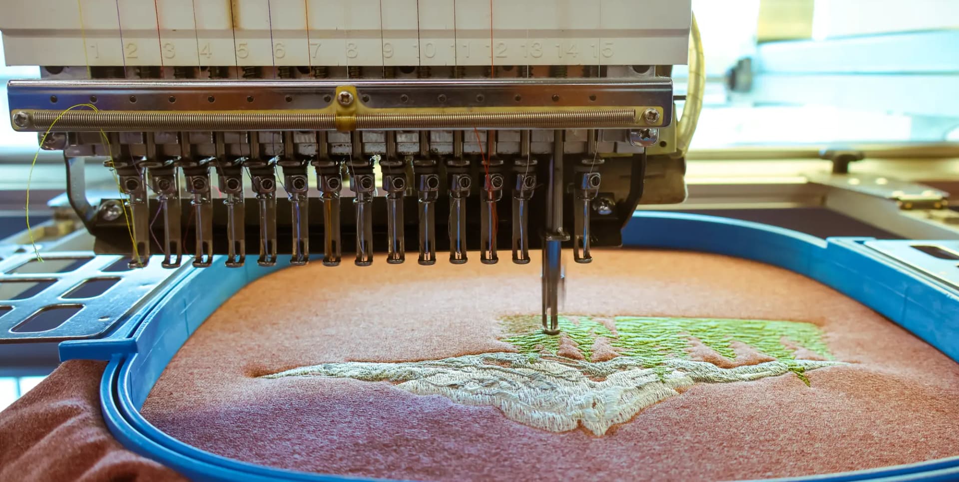 Embroidery head laying stitches into a hooped garment on the production floor
