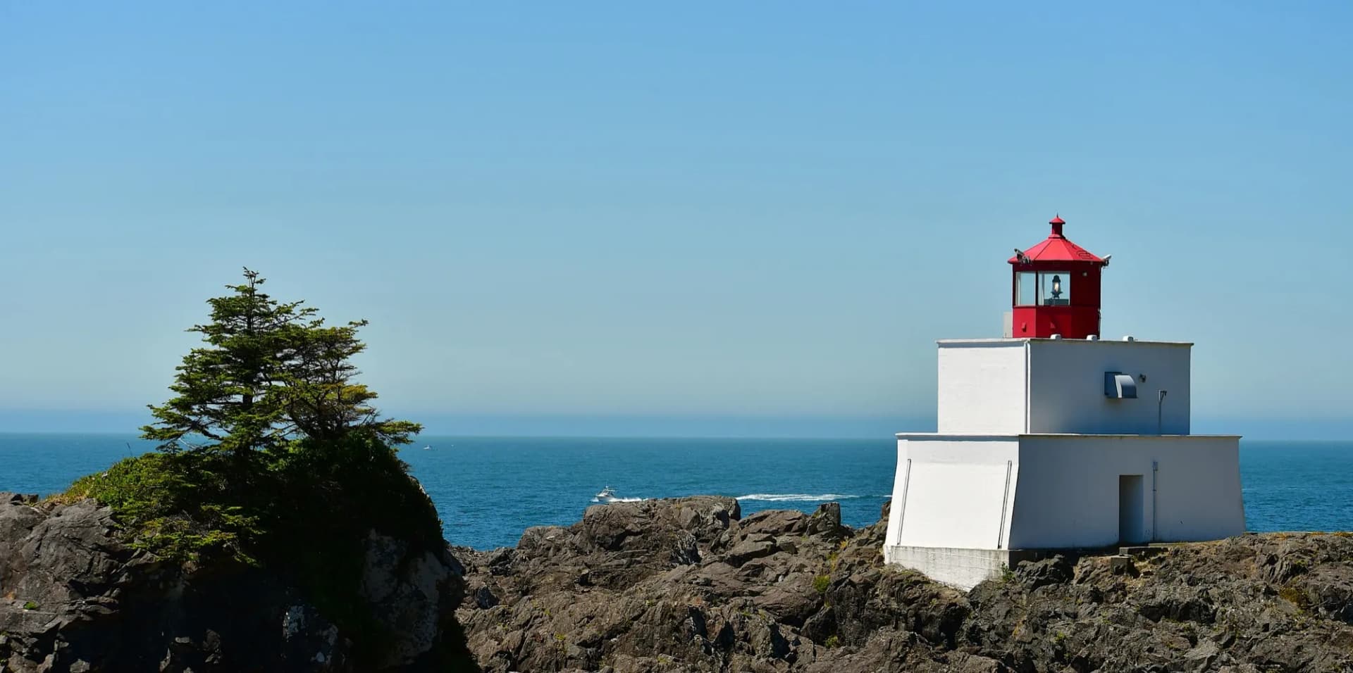 Amphitrite Point Lighthouse in Ucluelet, a squat white concrete light station on rocks above the Pacific